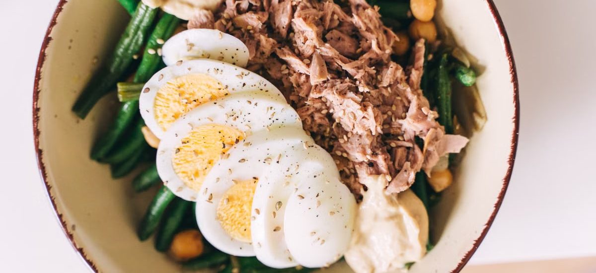 Delicious protein-packed bowl featuring tuna, boiled eggs, green beans, and hummus.